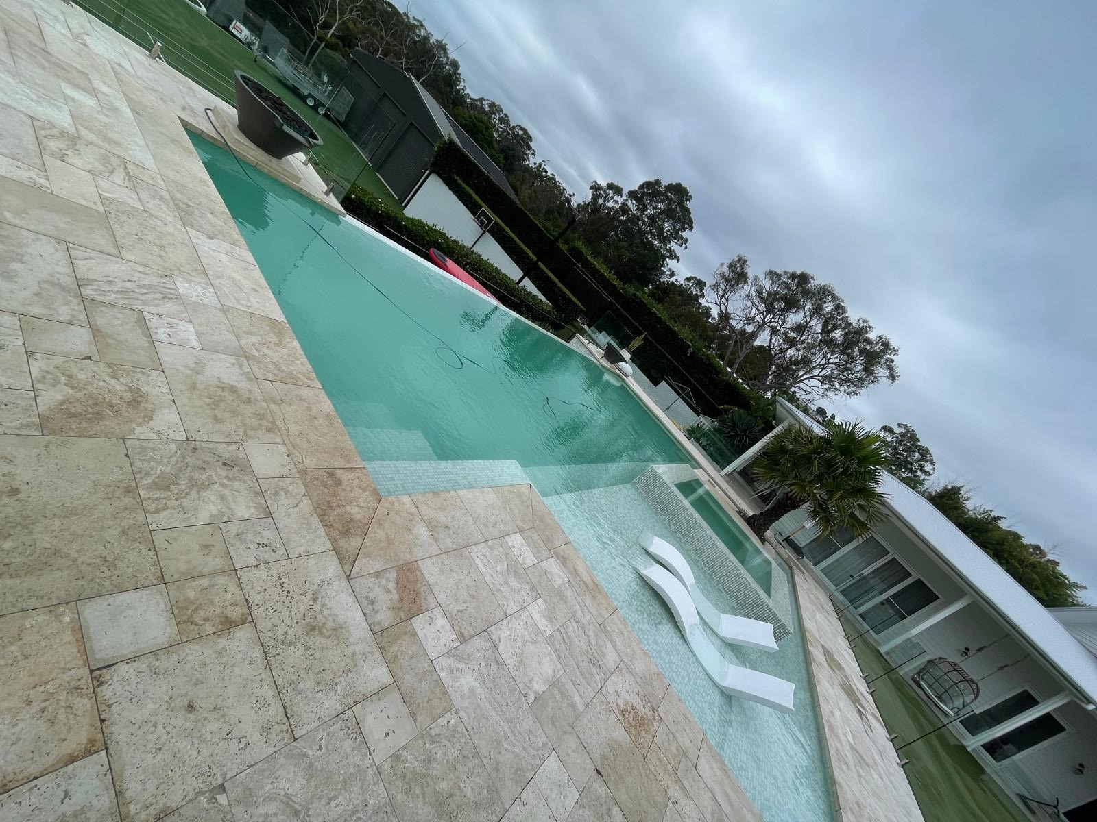 A freshly cleaned Melbourne backyard swimming pool with clear turquoise water after a professional pool cleaning service
